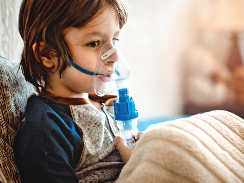 chlopiec podczas inhalacji w lozku z maseczka